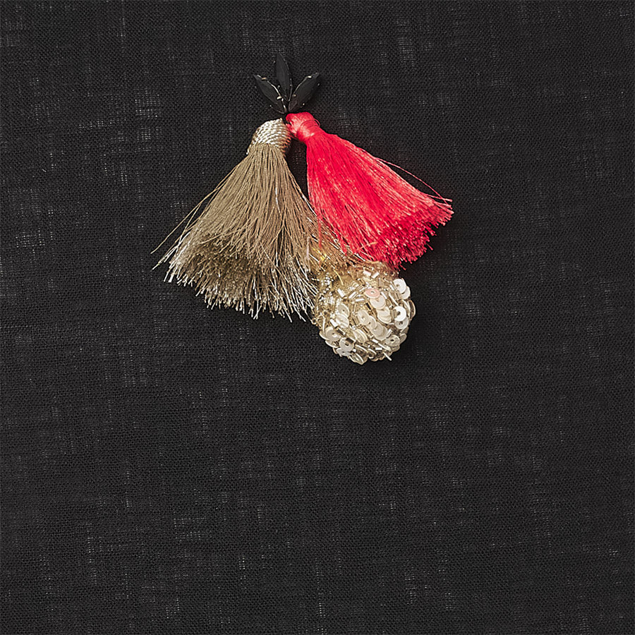 detail of a Black linen luxury cushion with grey stones & gold orange tassels